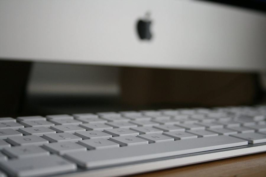 Picture of a computer keyboard in front of an iMac computer